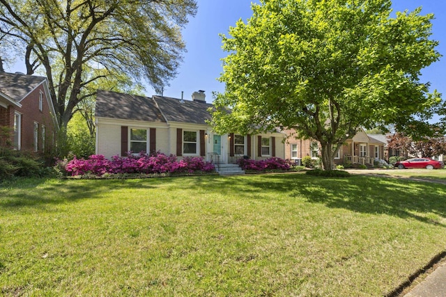 view of front of home featuring brick siding, a chimney, and a front lawn