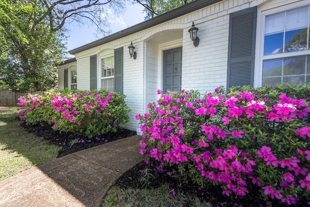 view of exterior entry with brick siding and fence