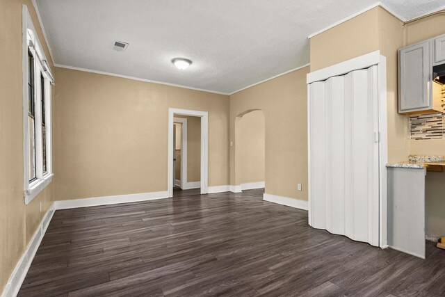 1072 Walk Rd, Memphis, TN 38109 - unfurnished living room with baseboards, crown molding, visible vents, dark wood finished floors, and arched walkways