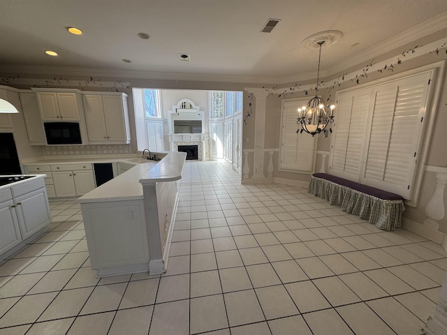 kitchen featuring crown molding, an inviting chandelier, a fireplace, a peninsula, and black appliances