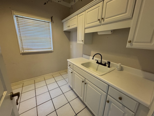 kitchen with a sink, light tile patterned floors, white cabinets, and light countertops