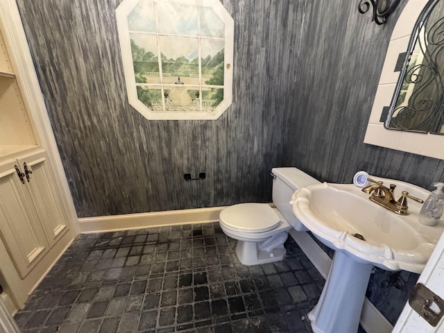 bathroom featuring toilet, stone finish floor, and a sink