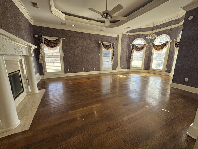 unfurnished living room with ornamental molding, ceiling fan with notable chandelier, visible vents, and a healthy amount of sunlight