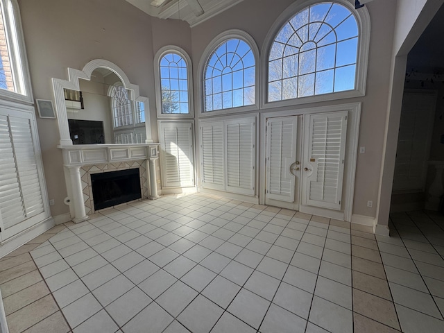 unfurnished living room with a wealth of natural light, a high ceiling, tile patterned flooring, and a tile fireplace