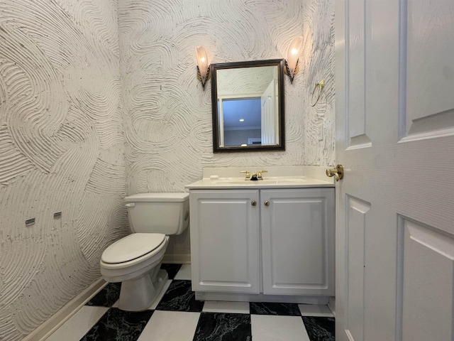 bathroom featuring toilet, marble finish floor, baseboards, and vanity