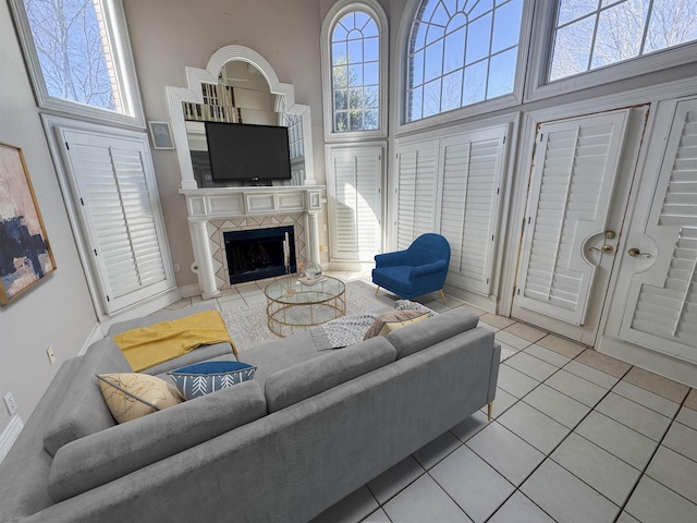 living area with tile patterned flooring, a towering ceiling, and a fireplace