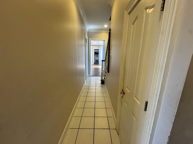 corridor featuring crown molding, baseboards, and light tile patterned flooring