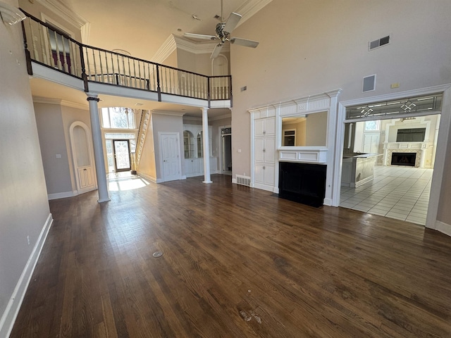 unfurnished living room with a fireplace with flush hearth, a towering ceiling, a ceiling fan, and baseboards