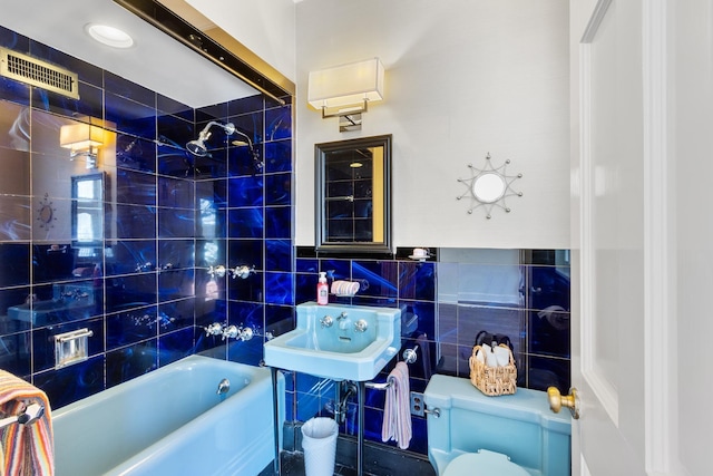bathroom featuring bathing tub / shower combination, visible vents, toilet, a sink, and tile walls