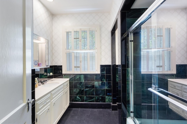 full bath featuring tile walls, a healthy amount of sunlight, vanity, wallpapered walls, and a wainscoted wall
