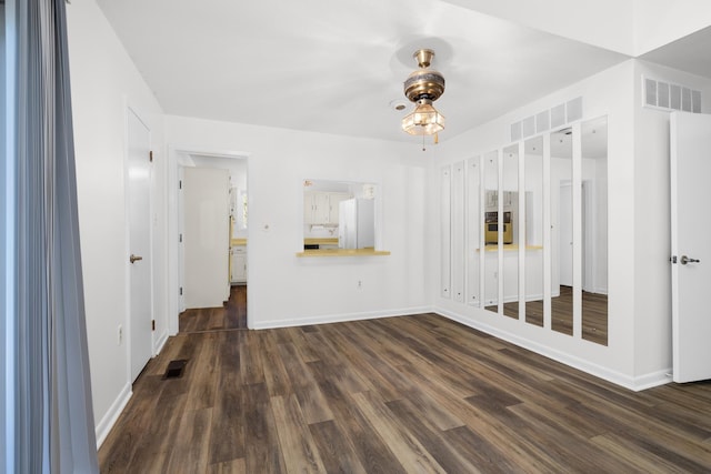 unfurnished living room featuring dark wood-style flooring and baseboards