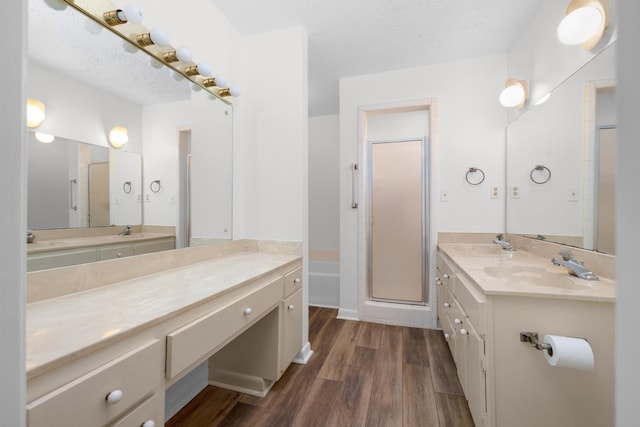 full bath featuring wood finished floors, a textured ceiling, vanity, and a stall shower