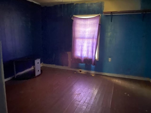 spare room with baseboards and hardwood / wood-style flooring