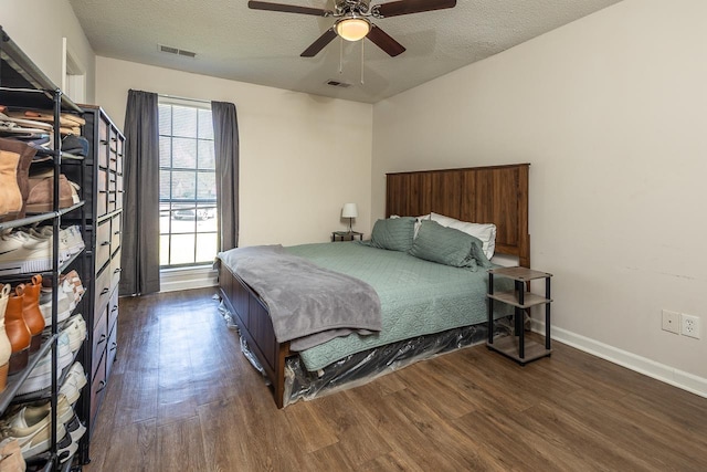 bedroom featuring baseboards, visible vents, dark wood-style flooring, and a textured ceiling
