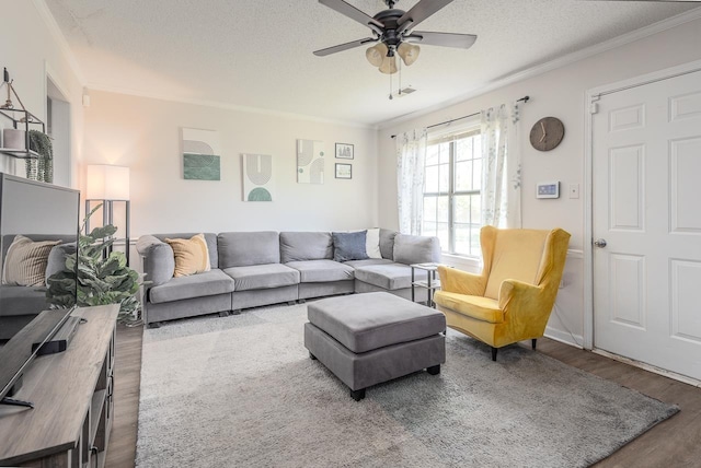 living area with a textured ceiling, wood finished floors, ceiling fan, and crown molding