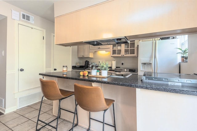 5718 Quince Rd Unit 4, Memphis, TN 38119 - kitchen featuring light tile patterned floors, glass insert cabinets, white refrigerator with ice dispenser, visible vents, and a breakfast bar area