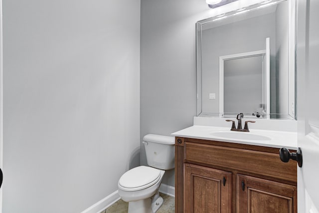 half bathroom with toilet, tile patterned floors, vanity, and baseboards