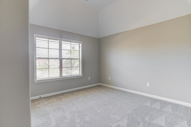 spare room with baseboards, vaulted ceiling, and carpet