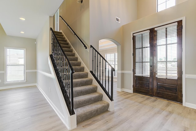 entrance foyer with french doors, visible vents, stairway, and arched walkways