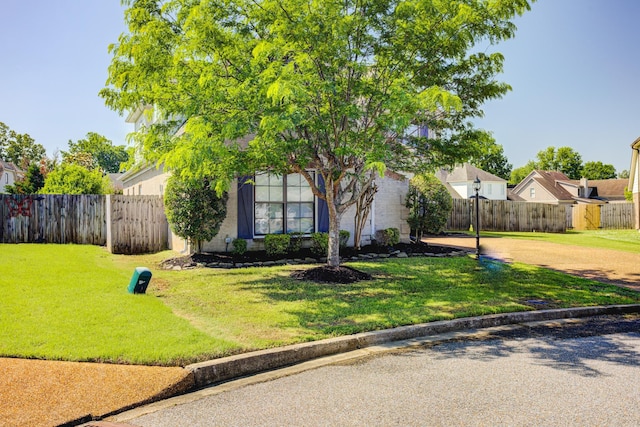 view of front of house featuring a front yard, fence, and driveway
