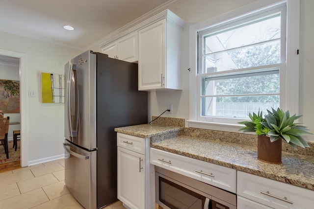 kitchen with light stone countertops, white cabinets, appliances with stainless steel finishes, and light tile patterned flooring