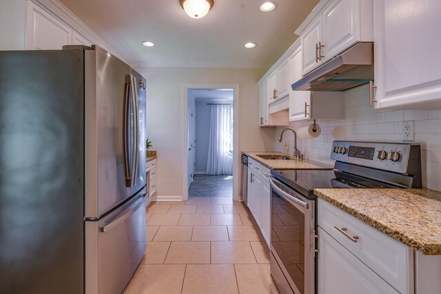 kitchen featuring under cabinet range hood, a sink, backsplash, white cabinets, and appliances with stainless steel finishes