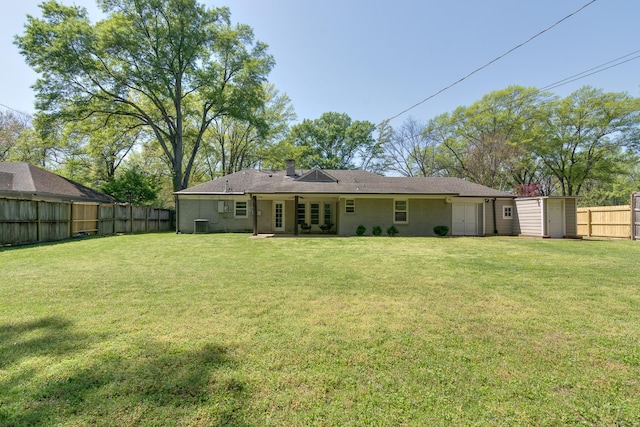 rear view of house featuring a chimney, a lawn, and a fenced backyard