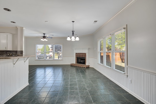 979 Welbeck Cv, Collierville, TN 38017 - unfurnished living room with ornamental molding, a fireplace, a wainscoted wall, visible vents, and ceiling fan with notable chandelier