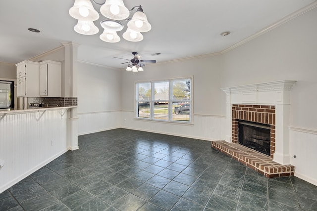 979 Welbeck Cv, Collierville, TN 38017 - unfurnished living room with wainscoting, ceiling fan with notable chandelier, ornamental molding, and a brick fireplace