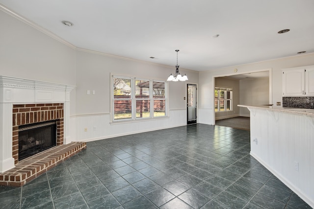 979 Welbeck Cv, Collierville, TN 38017 - unfurnished living room featuring crown molding, an inviting chandelier, a brick fireplace, and a healthy amount of sunlight