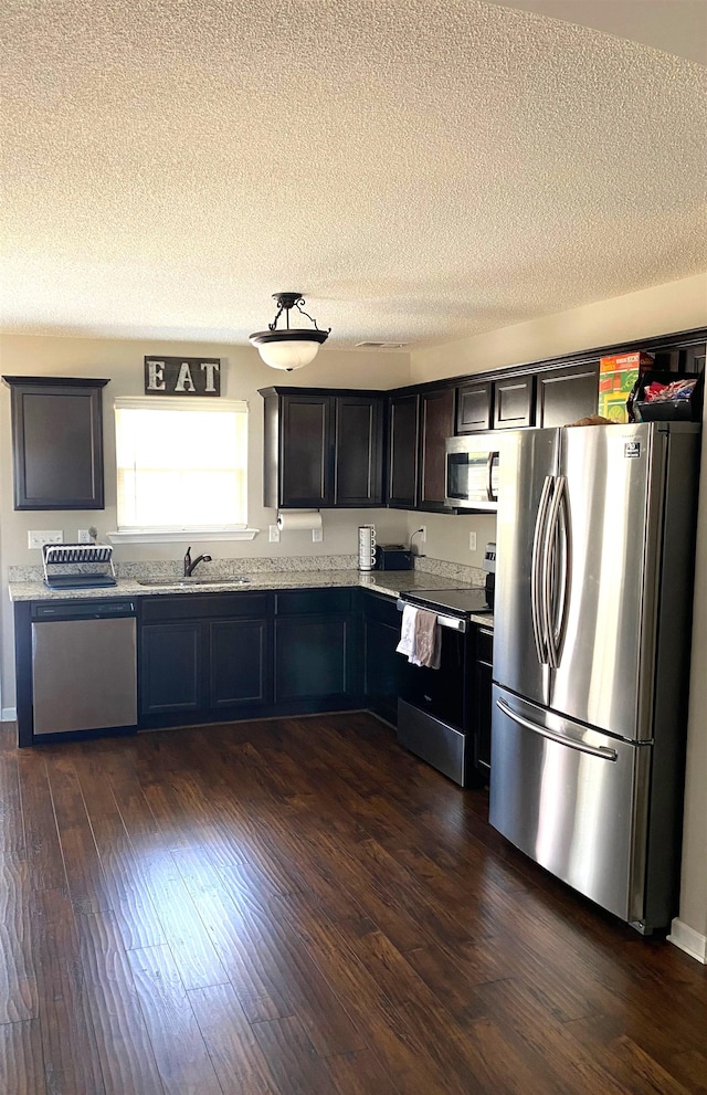 kitchen featuring a sink, dark wood finished floors, appliances with stainless steel finishes, and a textured ceiling