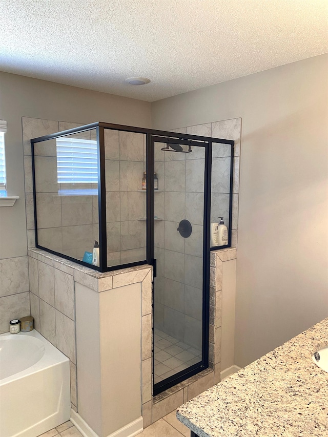 bathroom with a bath, a stall shower, tile patterned flooring, and a textured ceiling