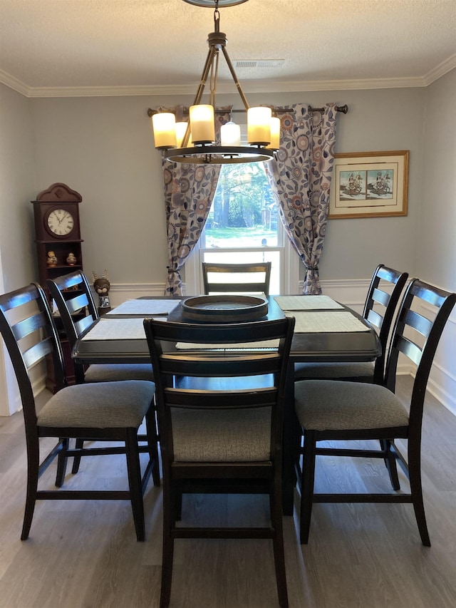 dining room with crown molding, wood finished floors, and a notable chandelier