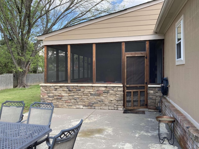 view of patio / terrace with a sunroom, outdoor dining area, and fence