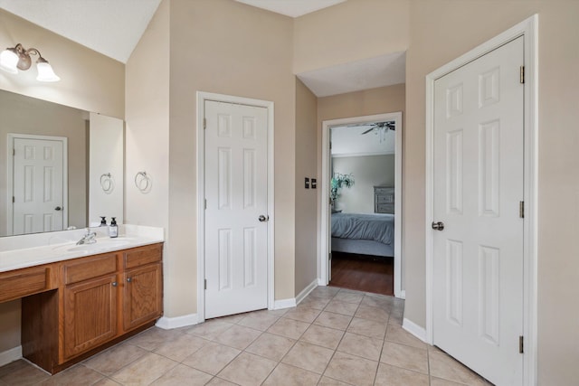bathroom with vanity, ensuite bath, tile patterned flooring, lofted ceiling, and baseboards