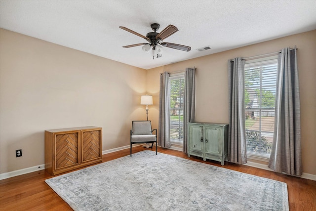sitting room with visible vents, baseboards, a ceiling fan, and wood finished floors