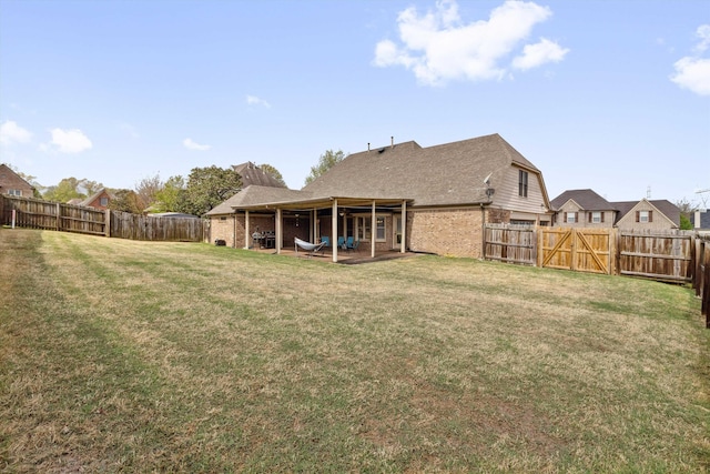 back of house with a yard, a fenced backyard, brick siding, and a patio