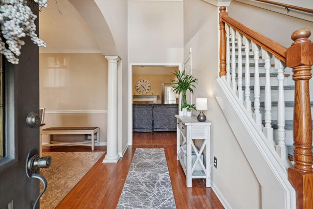 entryway with baseboards, decorative columns, arched walkways, and wood finished floors