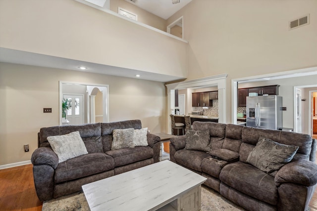 living area with visible vents, a high ceiling, and light wood-style floors