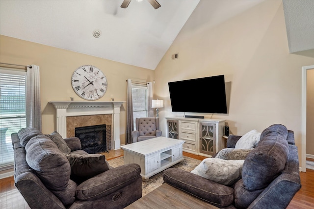 living area featuring visible vents, light wood-type flooring, a ceiling fan, a fireplace, and high vaulted ceiling