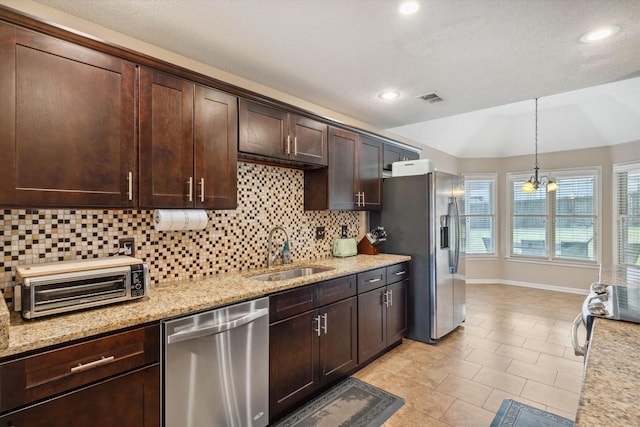 kitchen featuring dark brown cabinetry, visible vents, appliances with stainless steel finishes, a sink, and decorative backsplash