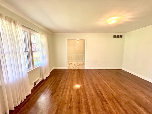spare room featuring crown molding, dark wood finished floors, and visible vents