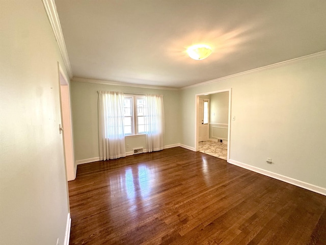 spare room featuring baseboards, ornamental molding, dark wood-style floors, and visible vents