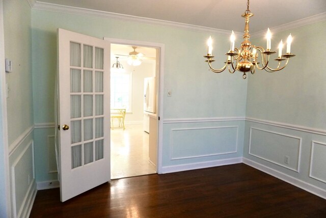 unfurnished dining area with crown molding, dark wood-style flooring, a notable chandelier, and wainscoting