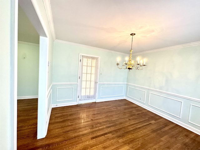 unfurnished dining area featuring crown molding, dark wood finished floors, a decorative wall, and a chandelier