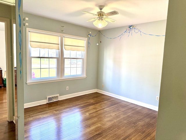 empty room featuring baseboards, ceiling fan, dark wood-type flooring, and visible vents