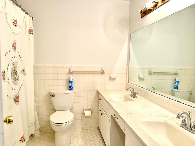 bathroom with a sink, wainscoting, toilet, and tile walls