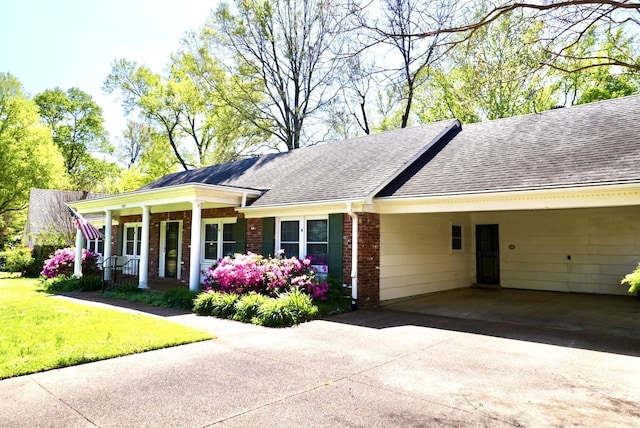 ranch-style house featuring covered porch, driveway, roof with shingles, a carport, and brick siding