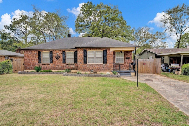 view of front of home featuring driveway, fence, a front lawn, and brick siding