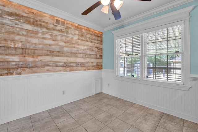 spare room featuring plenty of natural light, visible vents, a ceiling fan, and a wainscoted wall